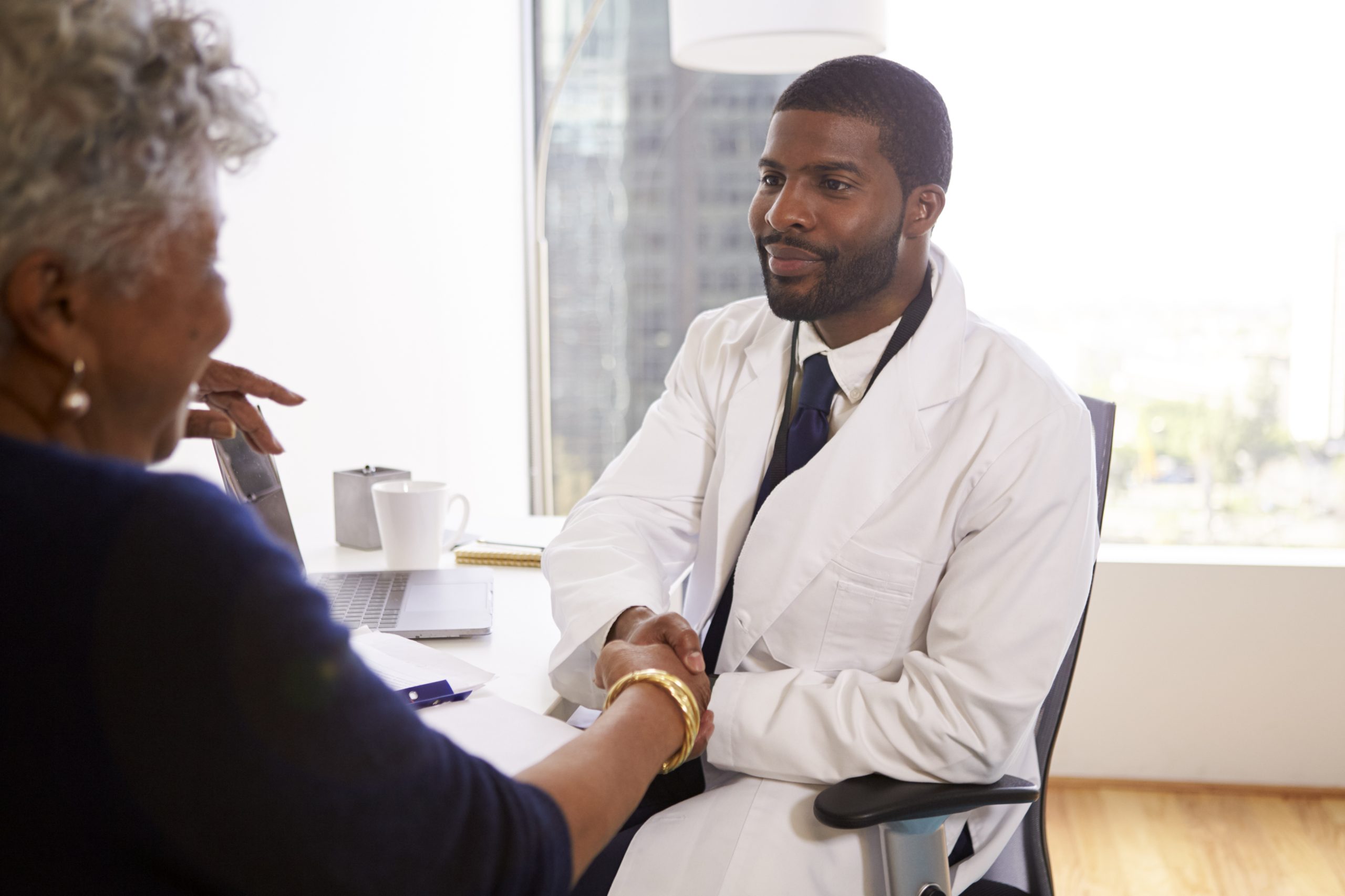 Senior Woman Shaking Hands With Male Doctor Cosmetic Surgeon In Office